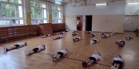 Klasa 1b podczas zajęć ruchowych na małej sali gimnastycznej.